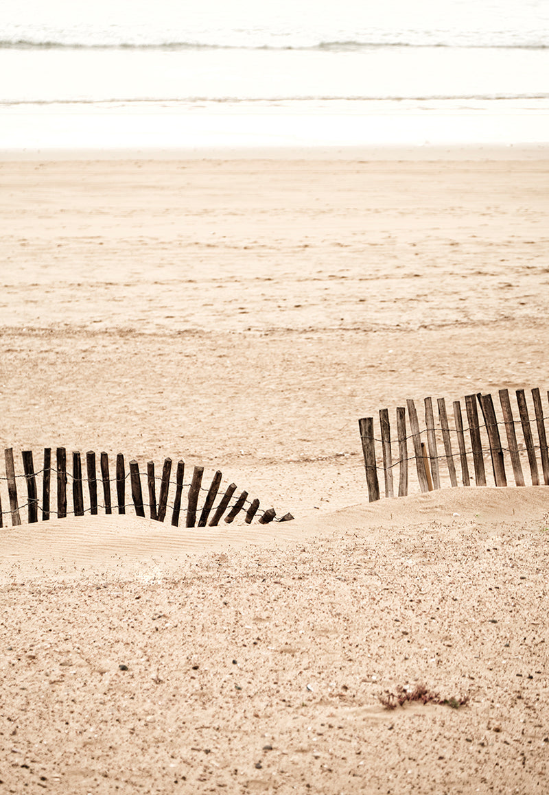 Et træ hegn på en strand i Marokko. Sandfarver. Enkle linjer.